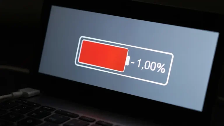 Laptop z paskiem baterii pokazującym szybkie rozładowywanie się i ikoną ostrzeżenia o niskim stanie baterii